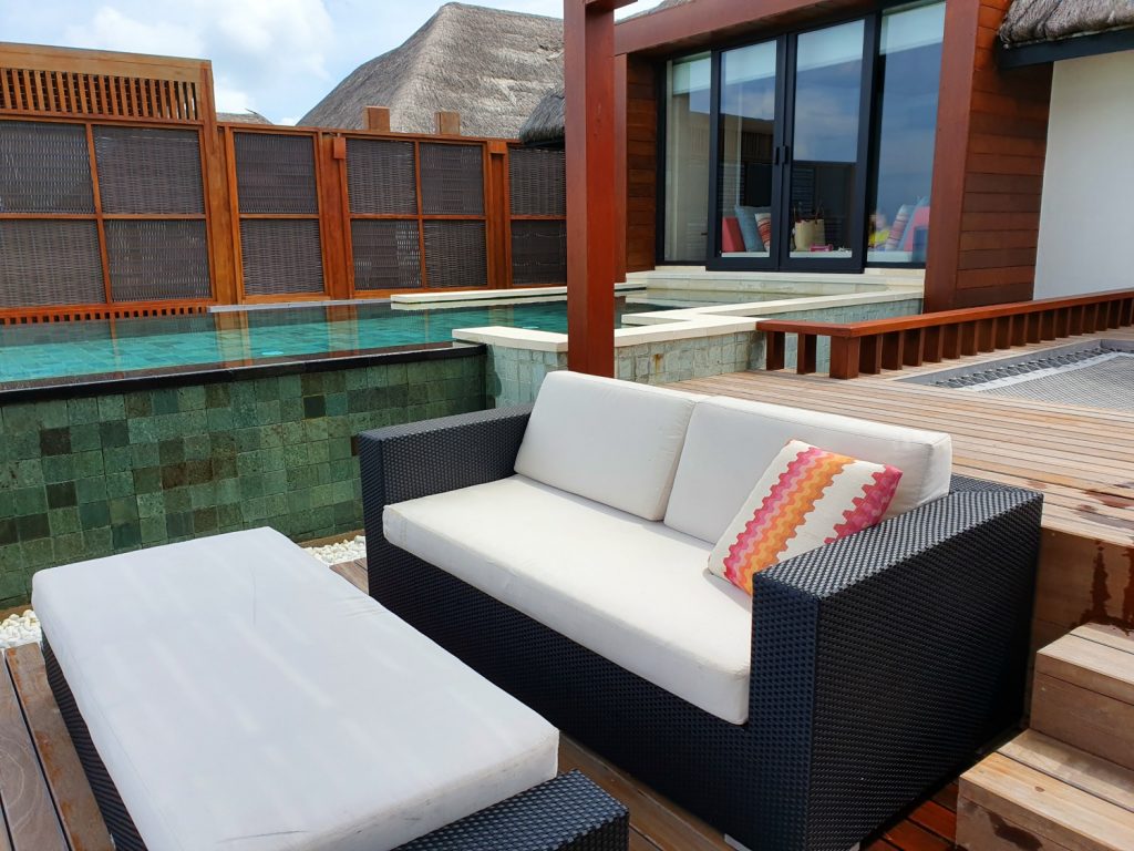 Sofa and private pool in the background on the deck of our water villa - a stay at Four Seasons Kuda Huraa with kids in the Maldives