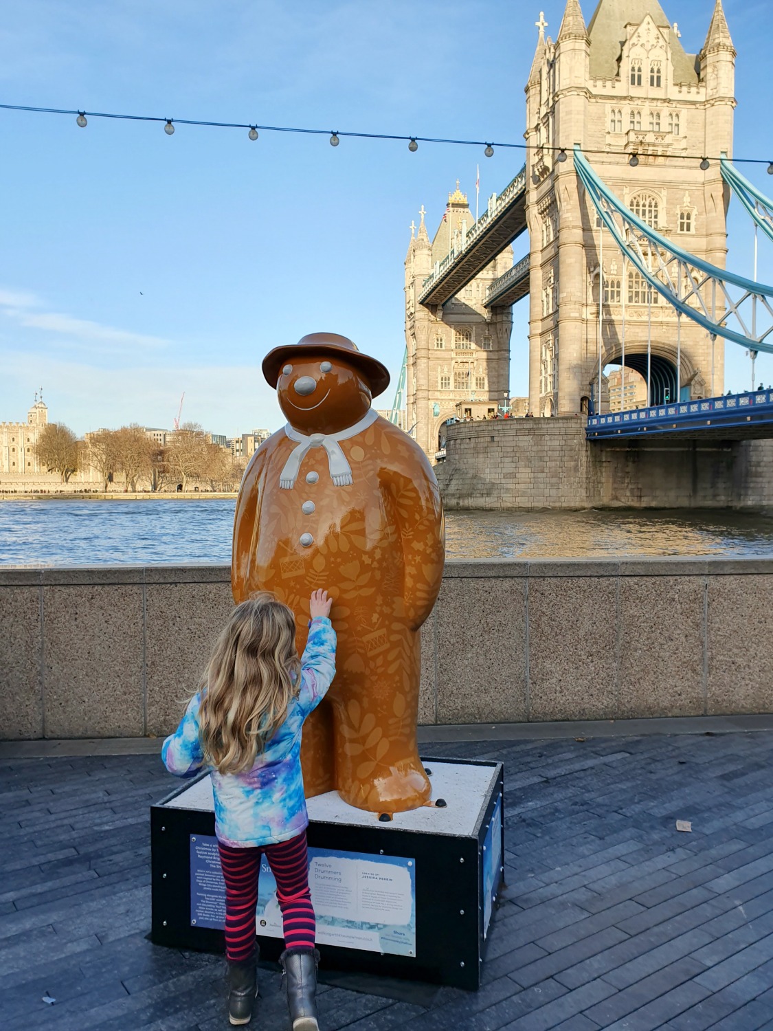 My daughter with one of the snowmen on the Christmas on the River trail in London with Tower Bridge in the background