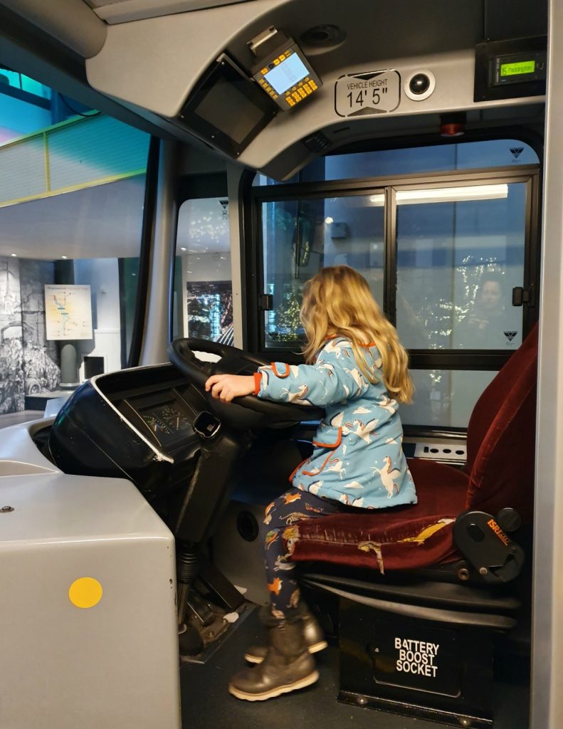 My daughter in the driver's seat of a bus at the London Transport Museum