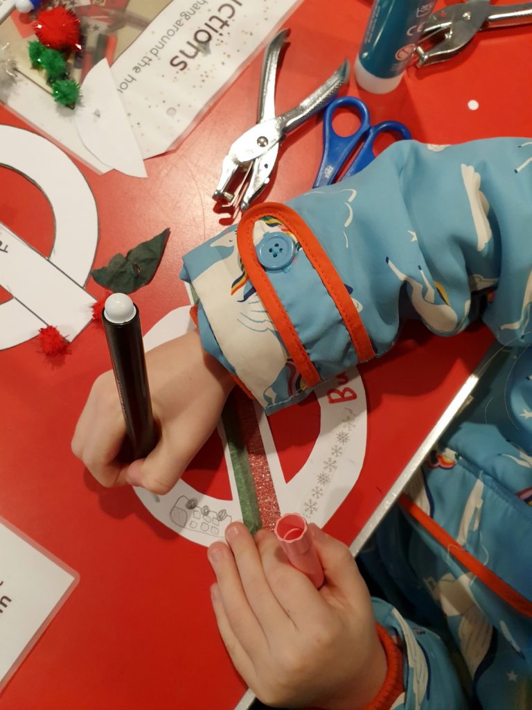 My daughter decorates a roundel as a Christmas tree decoration - one of the London Transport Museum Christmas activities on offer