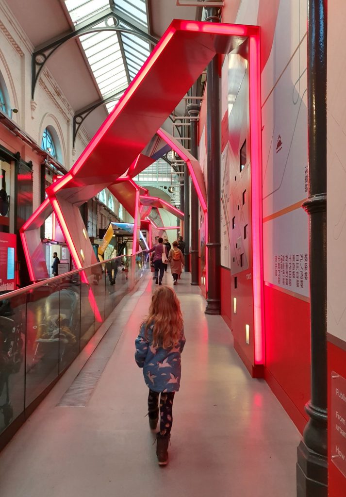 My daughter walks into the London Transport Museum toward the lifts