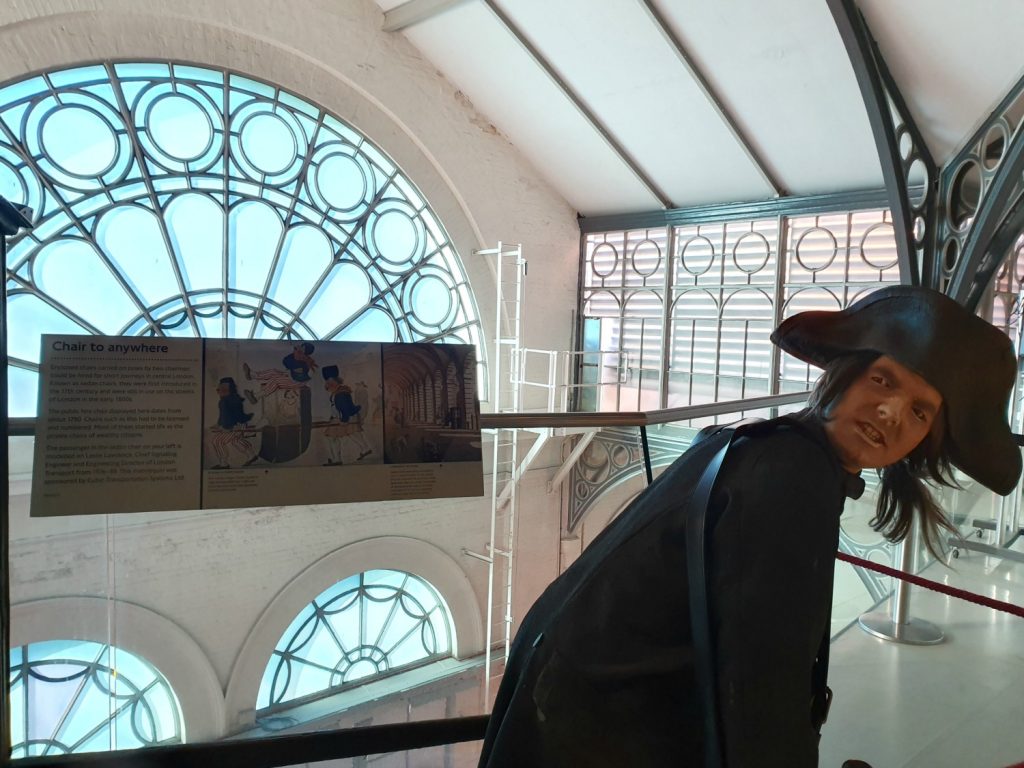 Model of a sedan chair carrier looking very unimpressed with life at the start of the London Transport Museum displays