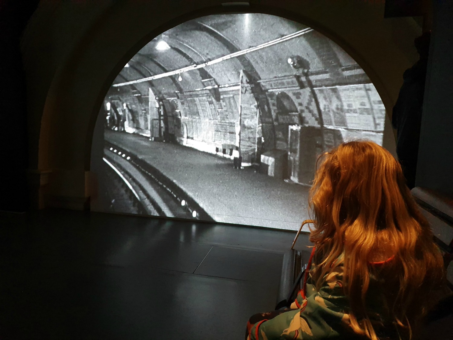 My daughter watching one of the movie clips filmed at Aldwych disused station in the Hidden London exhibition at the London Transport Museum