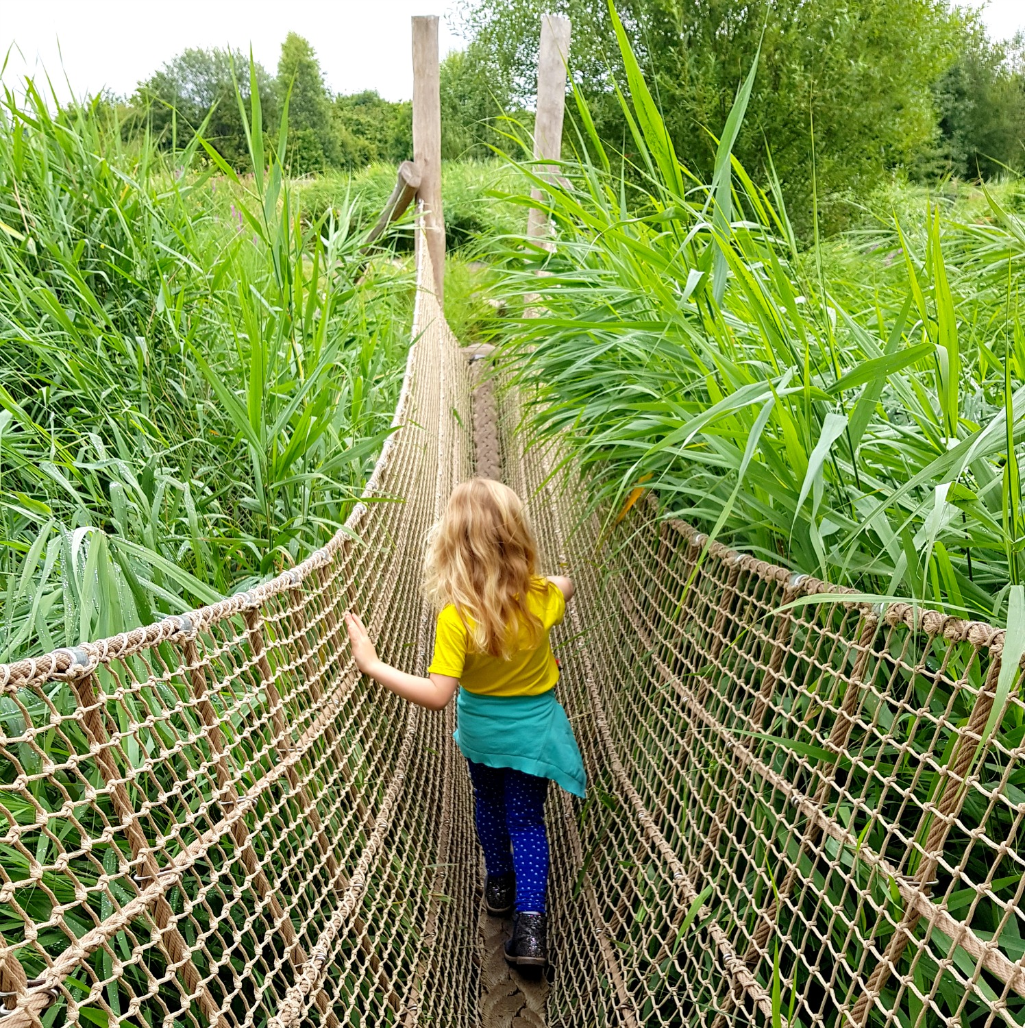 My daughter walks across the wild walk ropes course at the London Wetland Centre in Barnes, one of the best places to get outdoors in London with kids