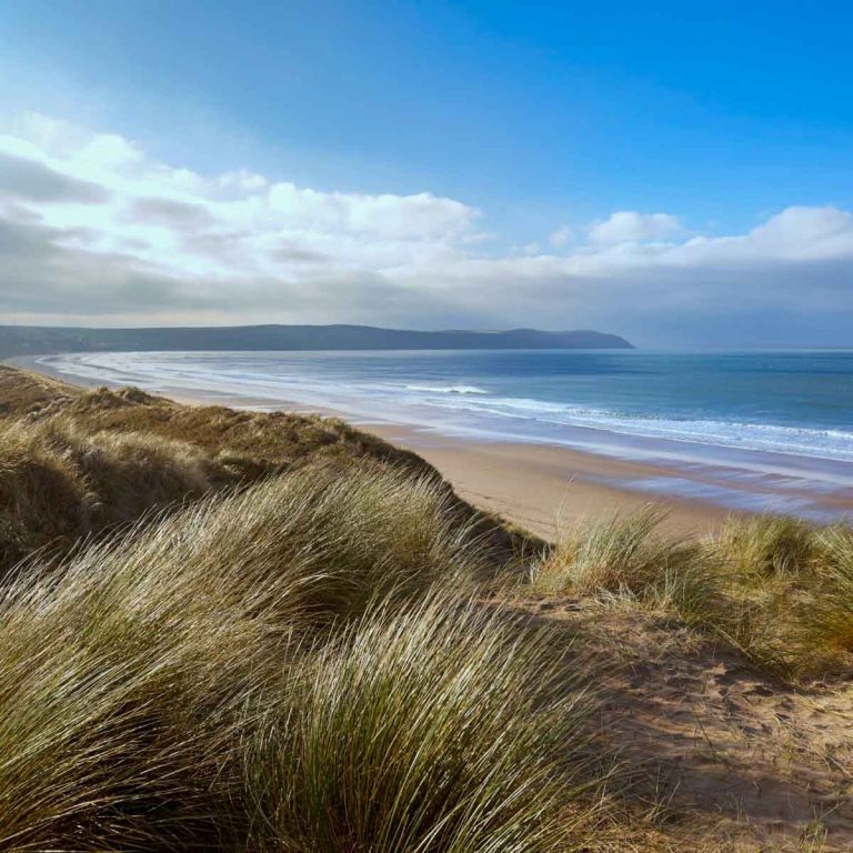 A view of Woolacombe beach in Devon through the sand dunes - hitting the beach is still one of my top things to do in Devon in winter