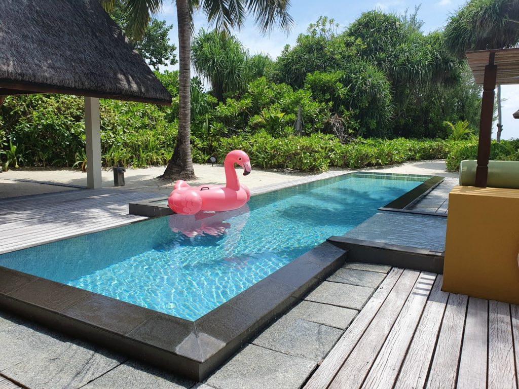 View of the pool at our beach villa, with an inflatable flamingo on the water and multiple options to lounge - one of the highlights of our stay at Landaa Giraavaru resort in the Maldives