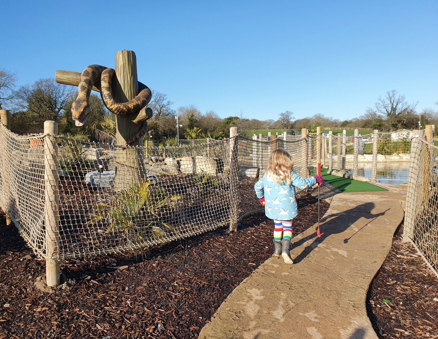 My daughter walks along a path by a snake on one of the courses at Lost Jungle London - visiting Lost Jungle adventure golf, Europe's biggest adventure golf course