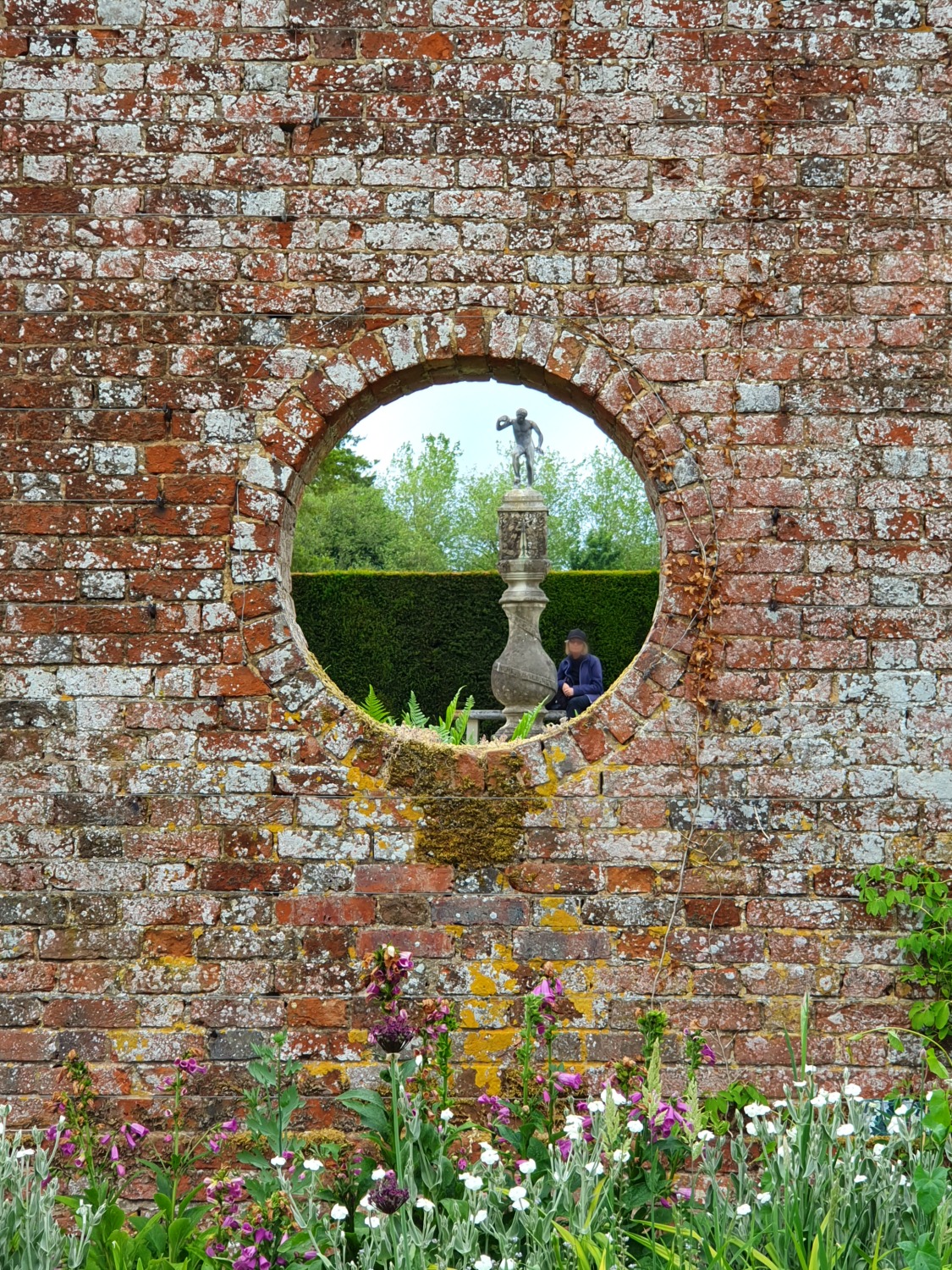 View of a statue in the formal gardens at Polesden Lacey through a hole in the wall of the formal gardens - our visit now the National Trust reopened some sites
