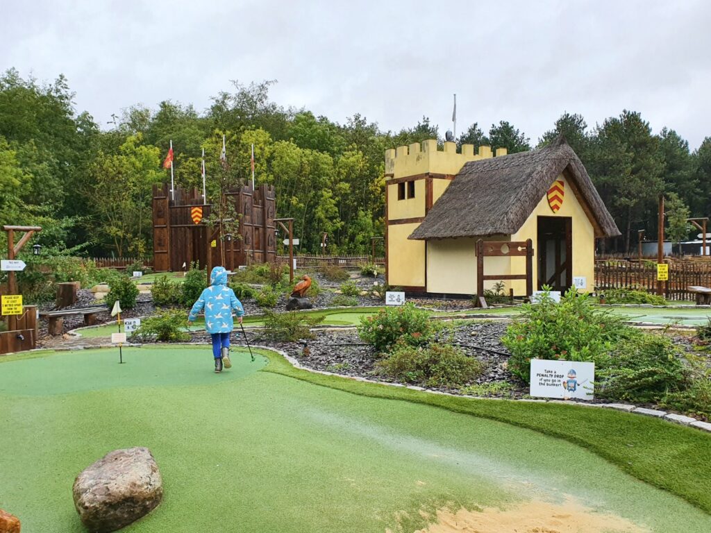 My daughter walks towards a replica tower among the mini golf holes at 1066 Adventure Golf, part of Golf World Stansted during a weekend in Essex with kids