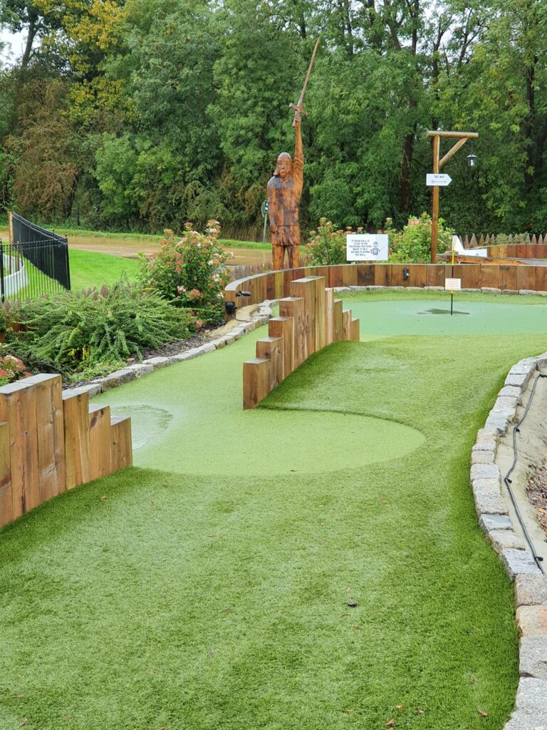 Wooden knight figure among the mini golf holes at 1066 Adventure Golf, part of Golf World Stansted during a weekend in Essex with kids