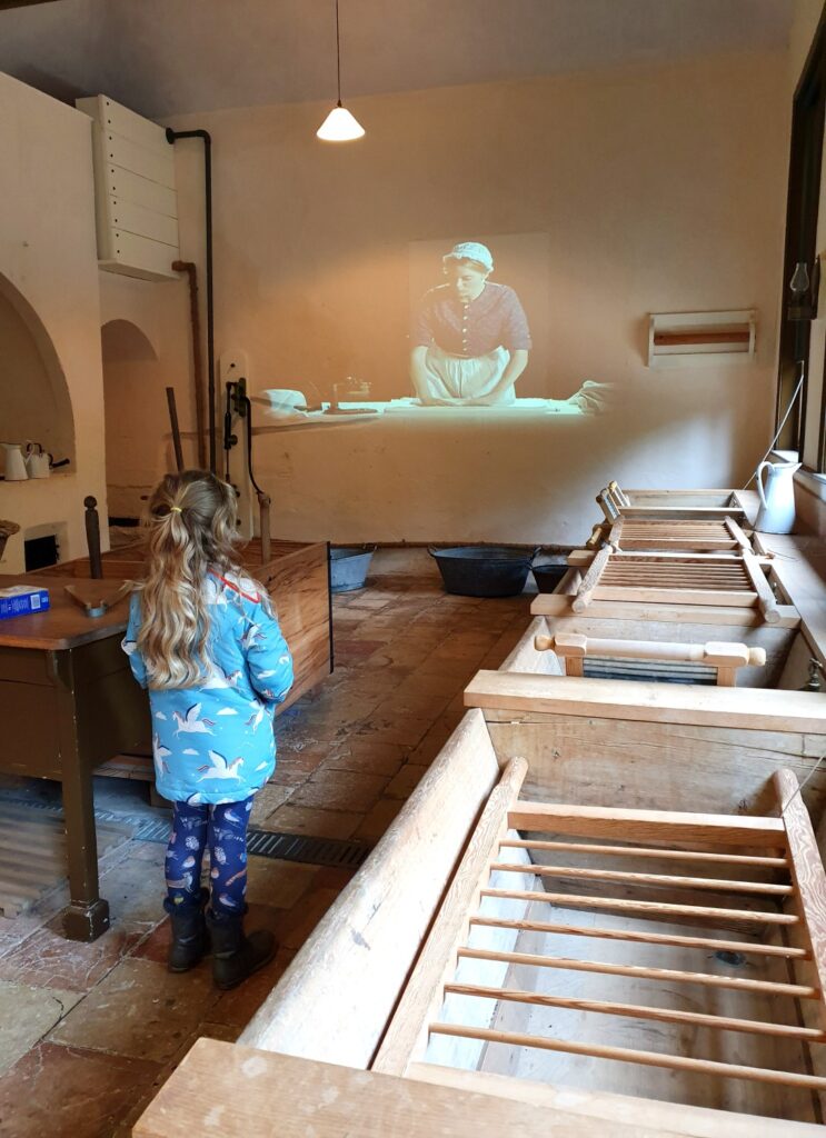 My daughter watches a video projected onto the wall in the old laundry at Audley End in Essex during a weekend in Saffron Walden with kids