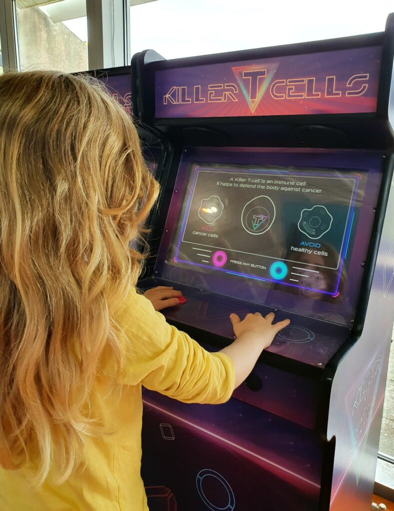 My daughter tries an arcade style game to fight cancer cells as one of the interactive displays at Winchester Science Centre with kids