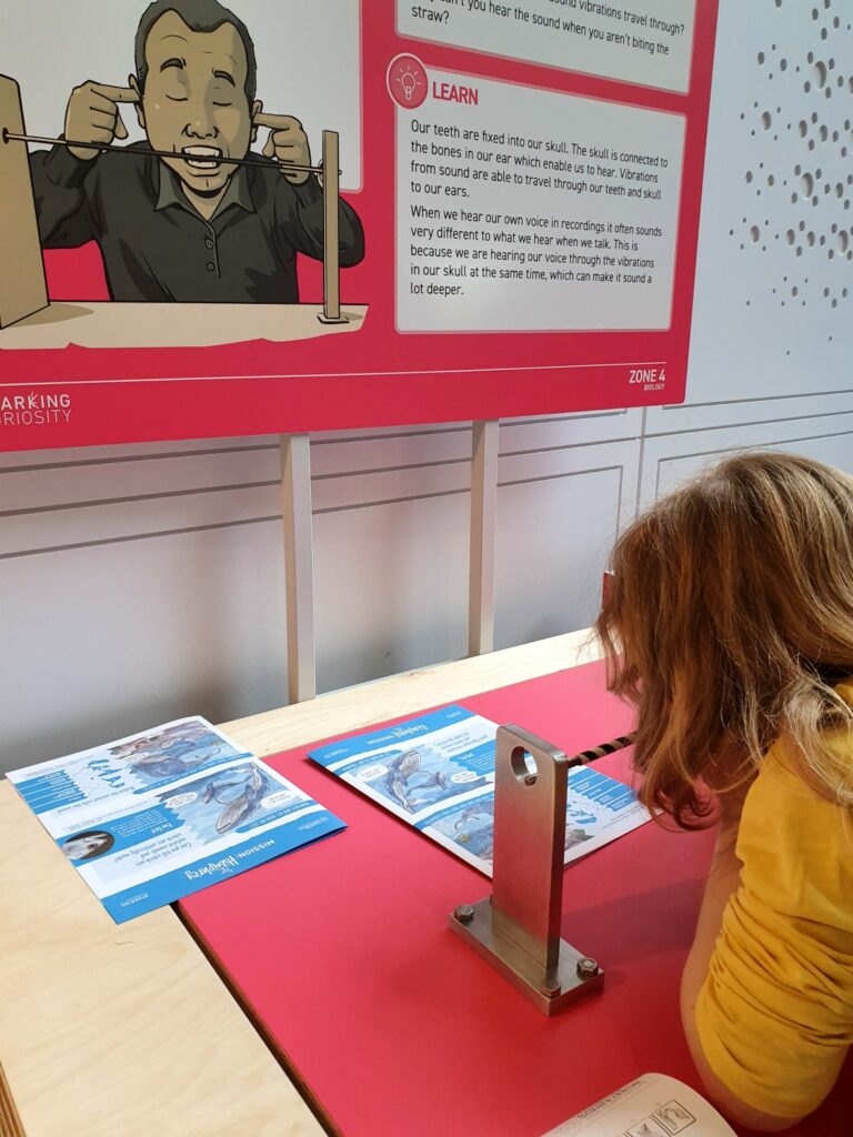 My daughter bites on a straw to feel the vibrations of sound - Winchester Science Centre review of the Hampshire family attraction