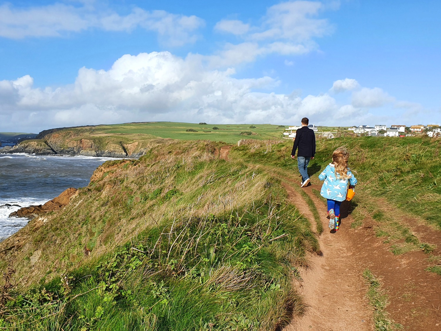 My husband and daughter walking along the cliff path by the seaside in the South Hams, Devon - one of our 2020 family travel highlights