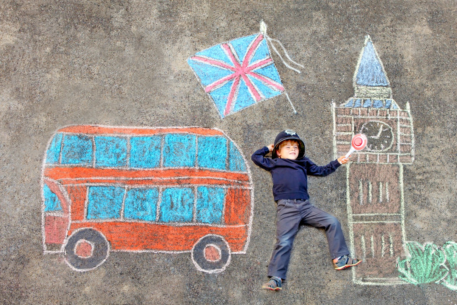 Boy in policeman's helmet against a chalk drawing of Big Ben, a red London doubledecker bus and Union Jack flag. The top 49 free things to do in London with kids