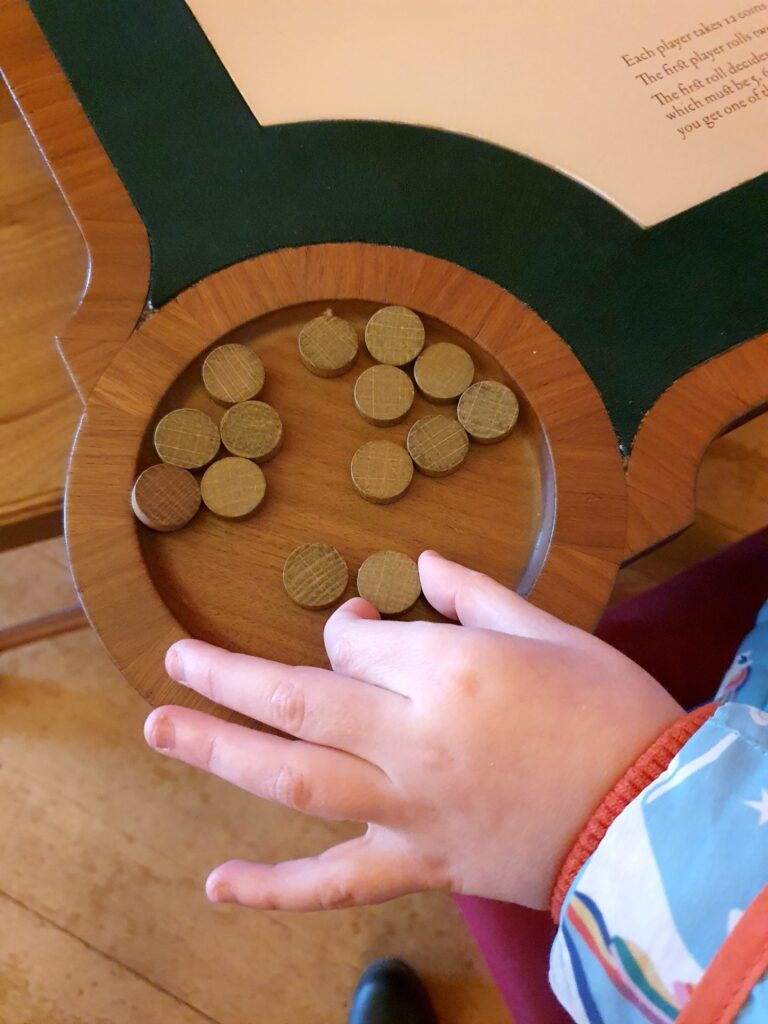 My daughter's hand reaches for one of the wooden betting chips on a gaming table at Kensington Palace