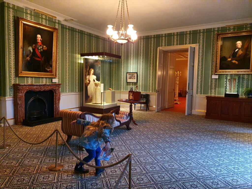 My daughter drops a curtsey in one of the empty rooms telling the story of Queen Victoria's childhood, and why now is a great time to visit Kensington Palace with kids