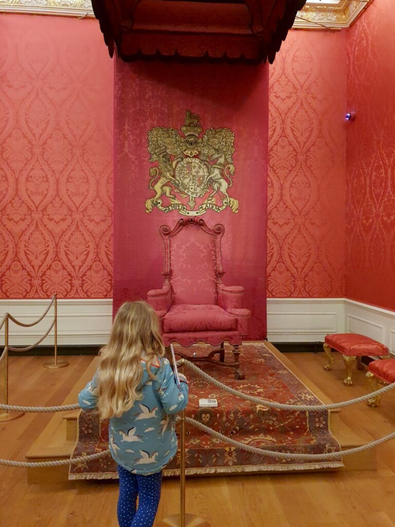 My daughter looks at the throne under a red canopy in Kensington Palace