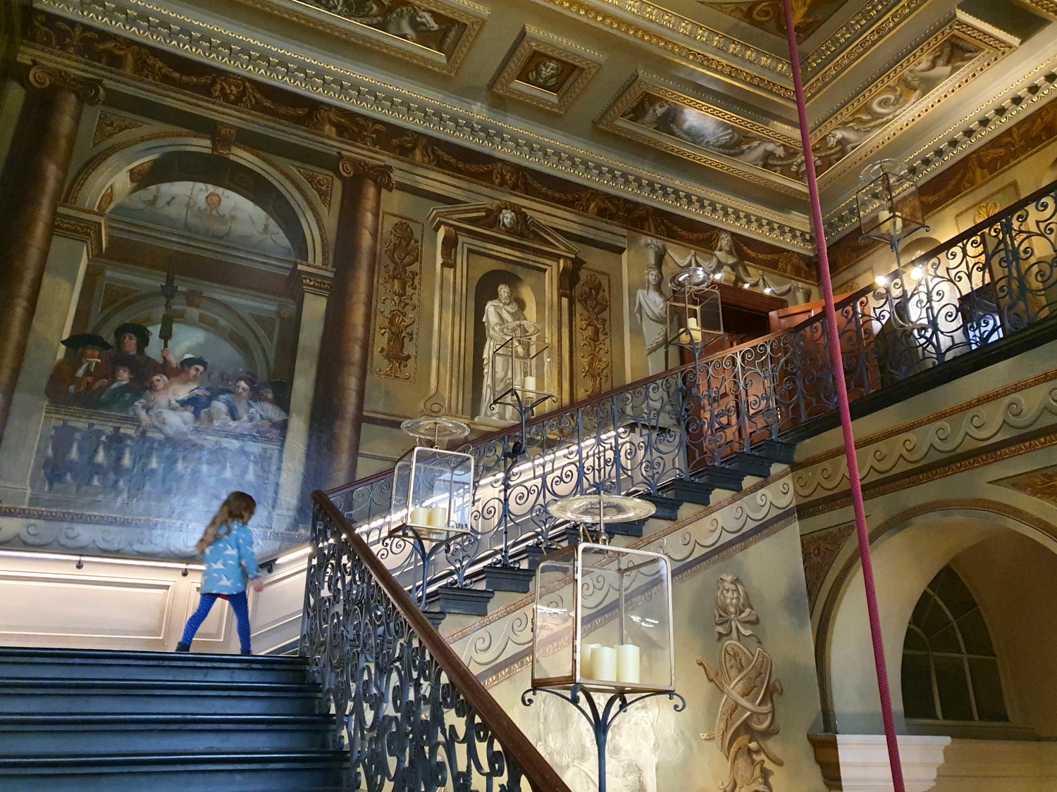 My daughter walks up the grand sweeping king's staircase during a visit to Kensington Palace with kids
