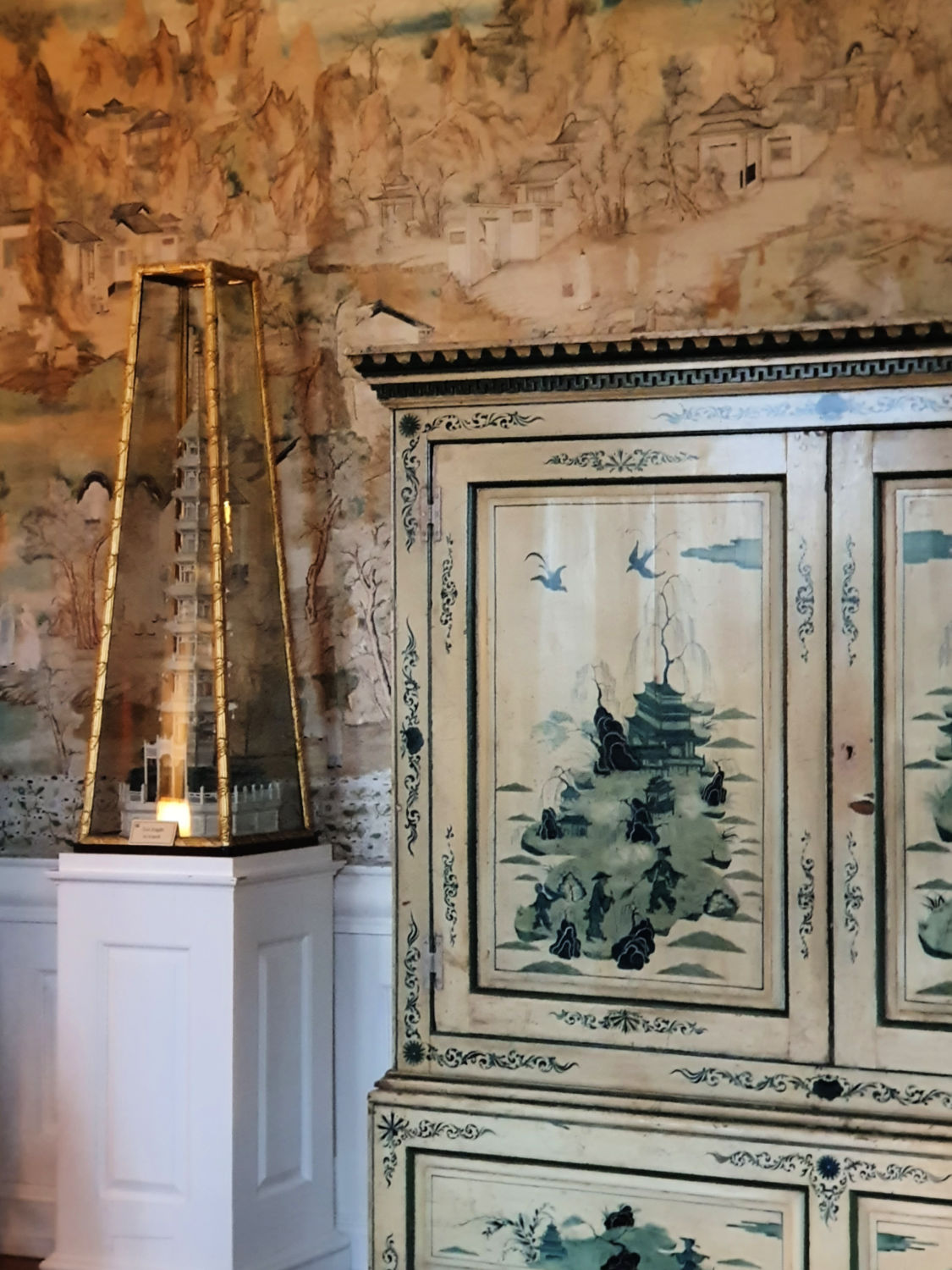 Close up of a mini pagoda in a glass case that doubles as an earthquake detector, alongside a Chinese style cabinet in one of the bedrooms - visiting Blickling Hall with kids