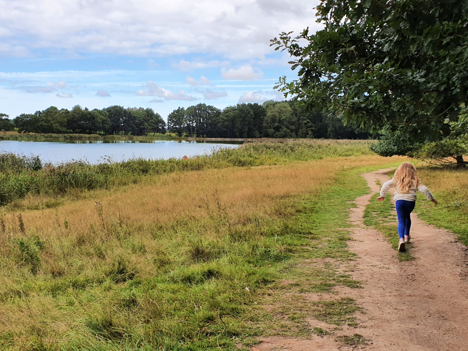 My daughter runs along the path by the lake at Blickling Hall near Norwich - a day out at Blickling Hall with kids