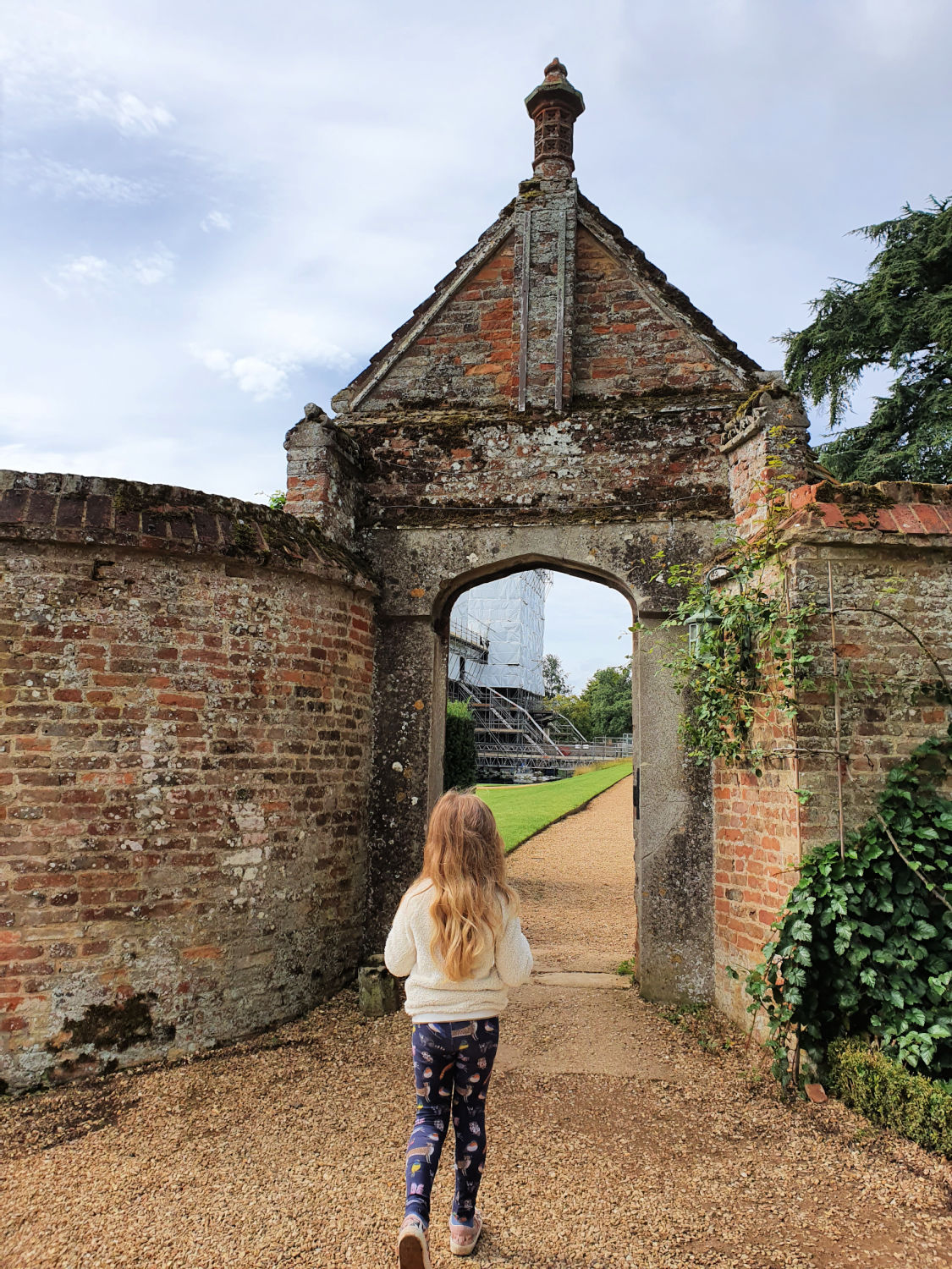 My daughter walks towards the gateway in the walls at Oxburgh House - a day out with kids at Oxburgh Hall in Norfolk
