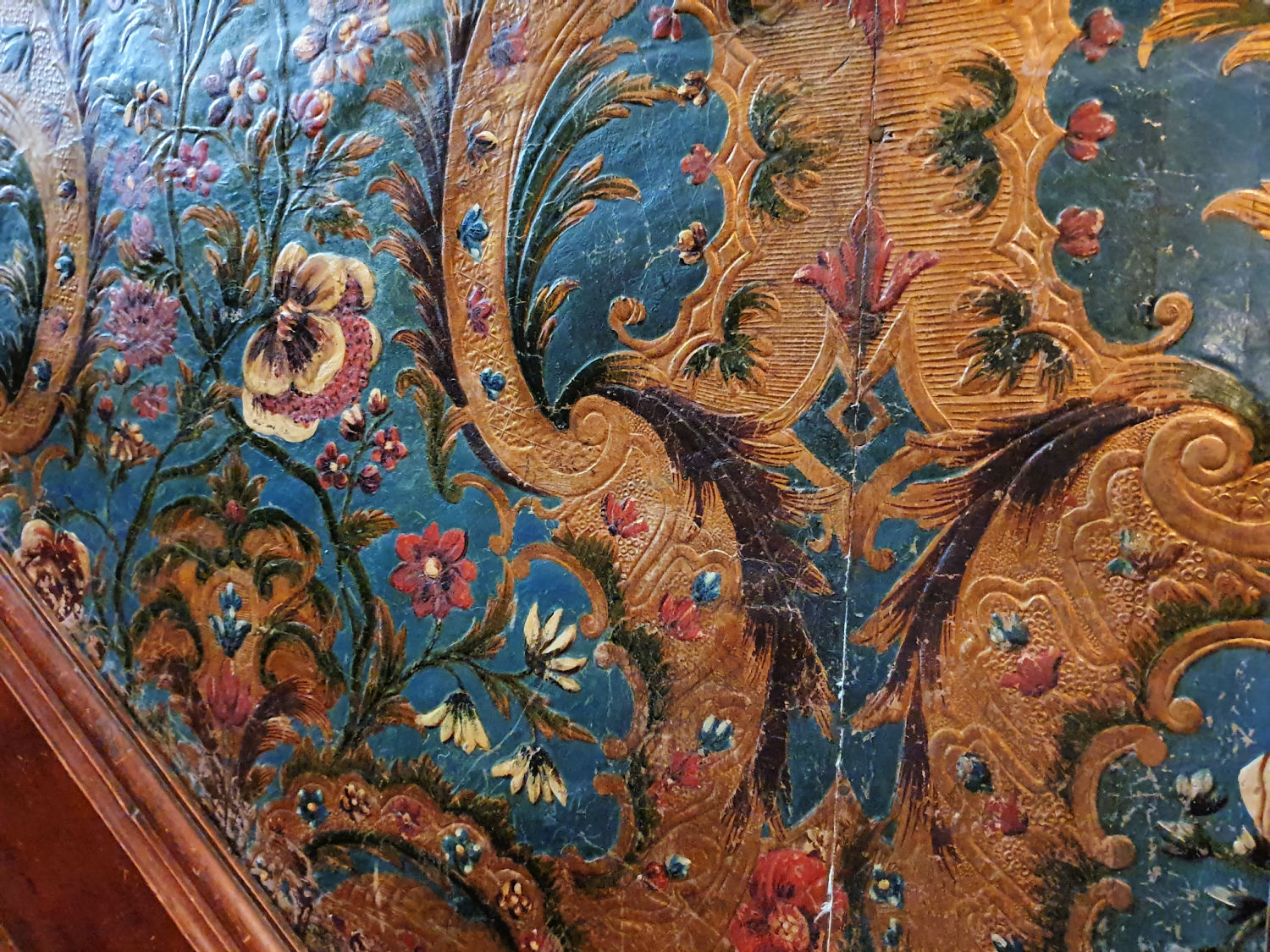 Gold and blue leather wallpaper with white and pink flowers on the staircase at Oxburgh Hall - a day out in Norfolk with kids