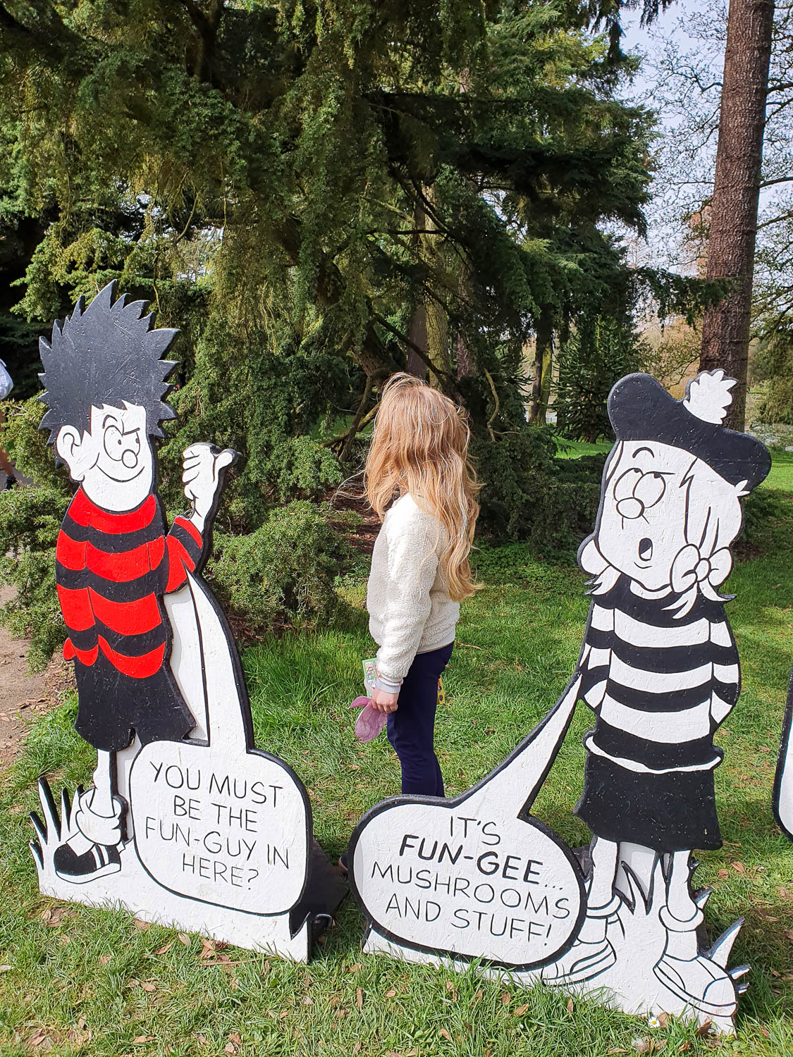 My daughter with two cut outs of Beano characters talking about funghi as part of the kids trail for Easter at Kew Gardens