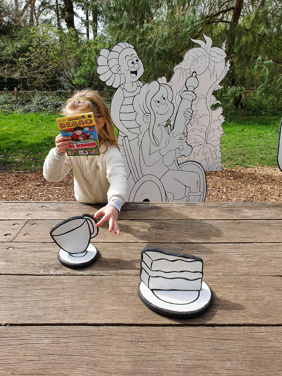 My daughter with her Beano trail magazine reaches for a cut-out cup along the Beano kids trail for Easter at Kew Gardens