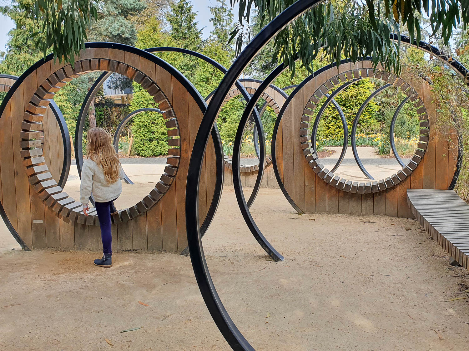 My daughter climbs through a round wooden structure in the Children's Garden at Kew Gardens