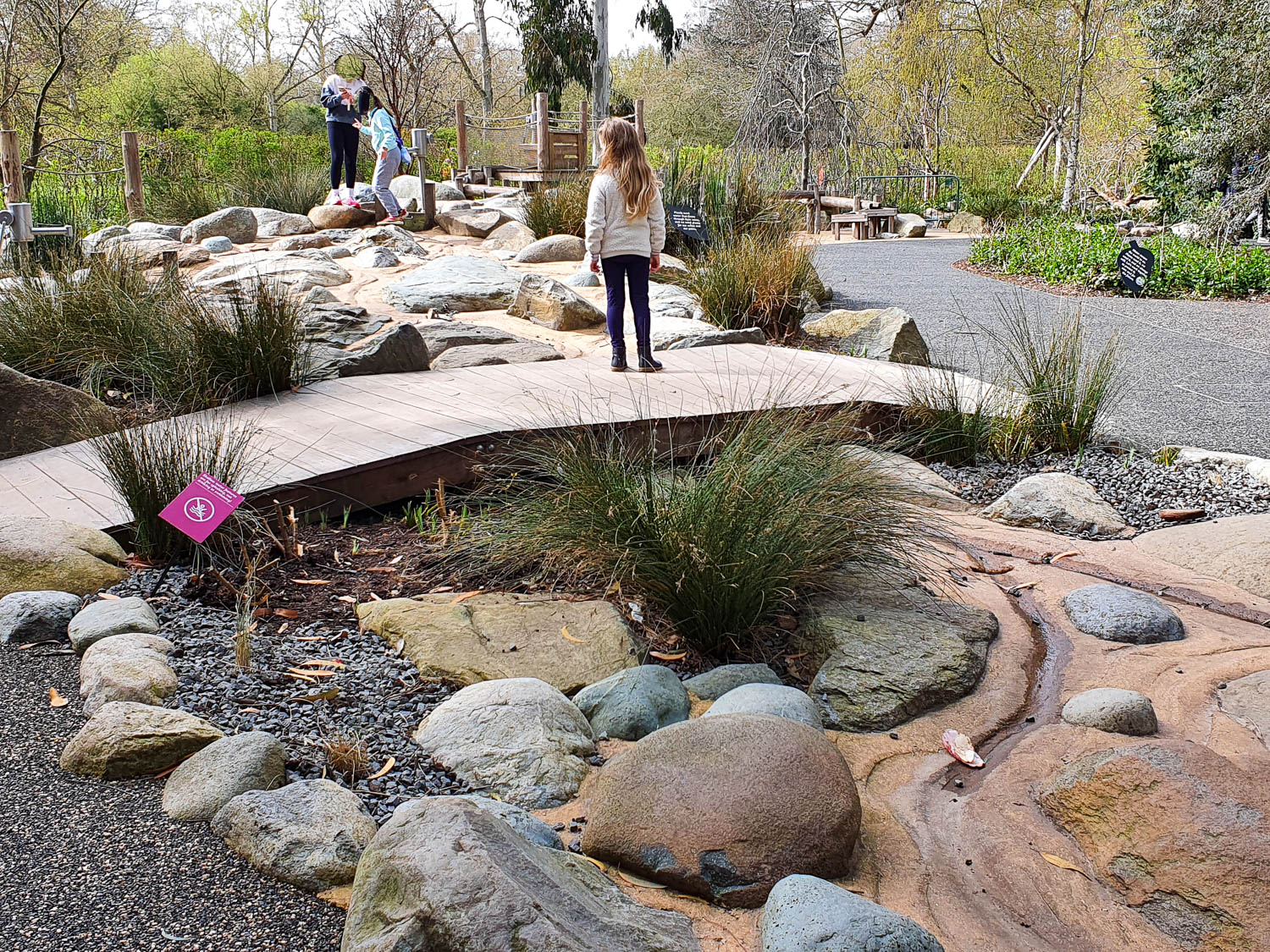 My daughter stands on a bridge in the Children's Garden at Kew Gardens in the section representing water (although with the water turned off)