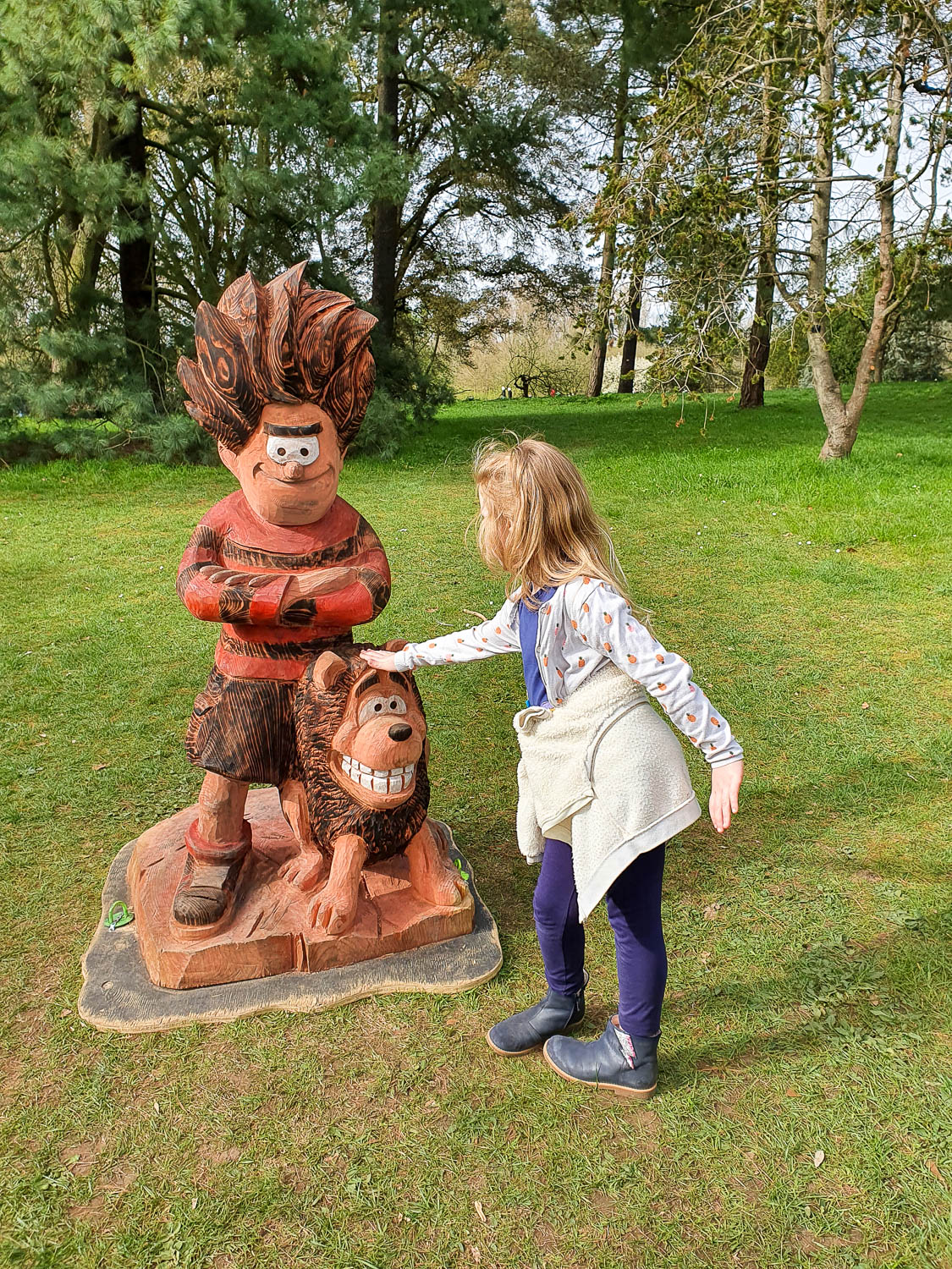My daughter pats the statue of Gnasher next to Dennis the Menace at the end of the special kids' trail for Easter at Kew