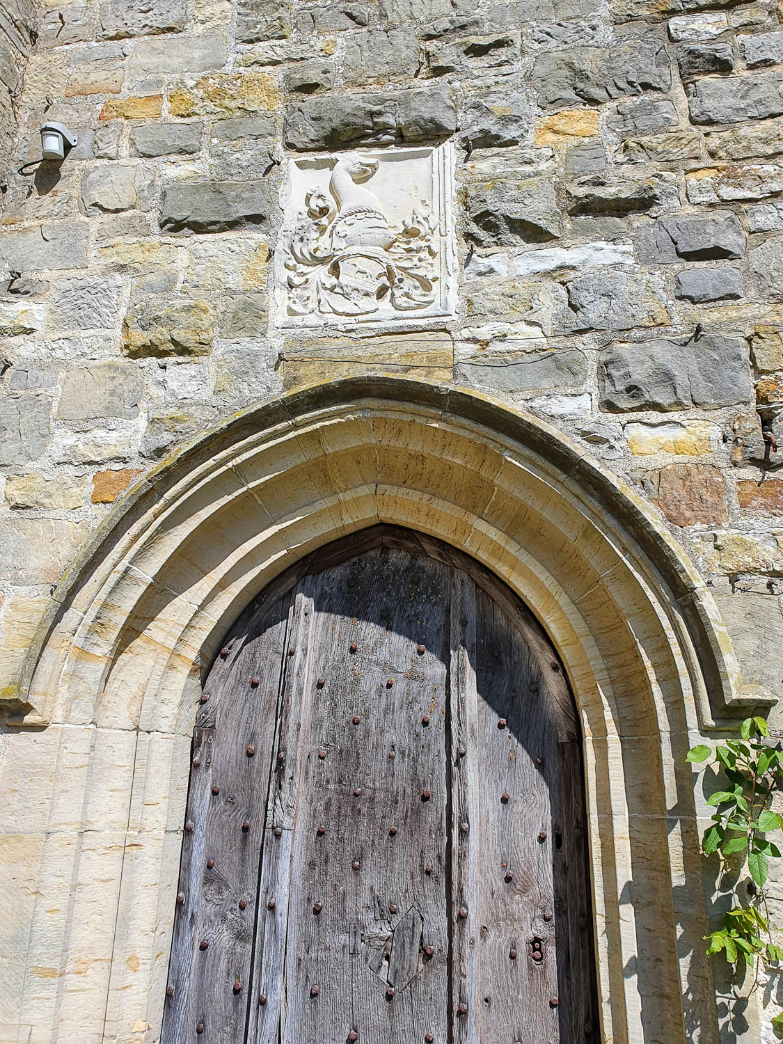 View of a carving above an old studded wooden door in an archway of the house at Nymans National Trust - visiting Sussex with kids