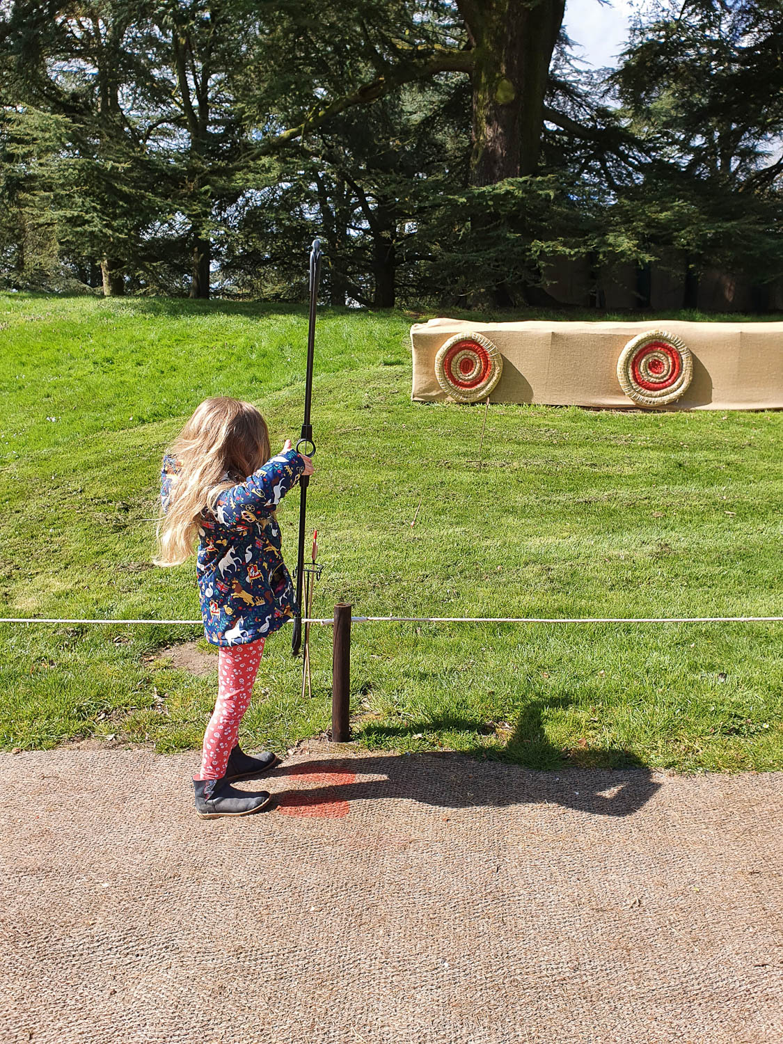 My daughter holds a bow aimed towards the targets as part of the archery activity at Warwick Castle - my review of a day out at Warwick Castle with kids