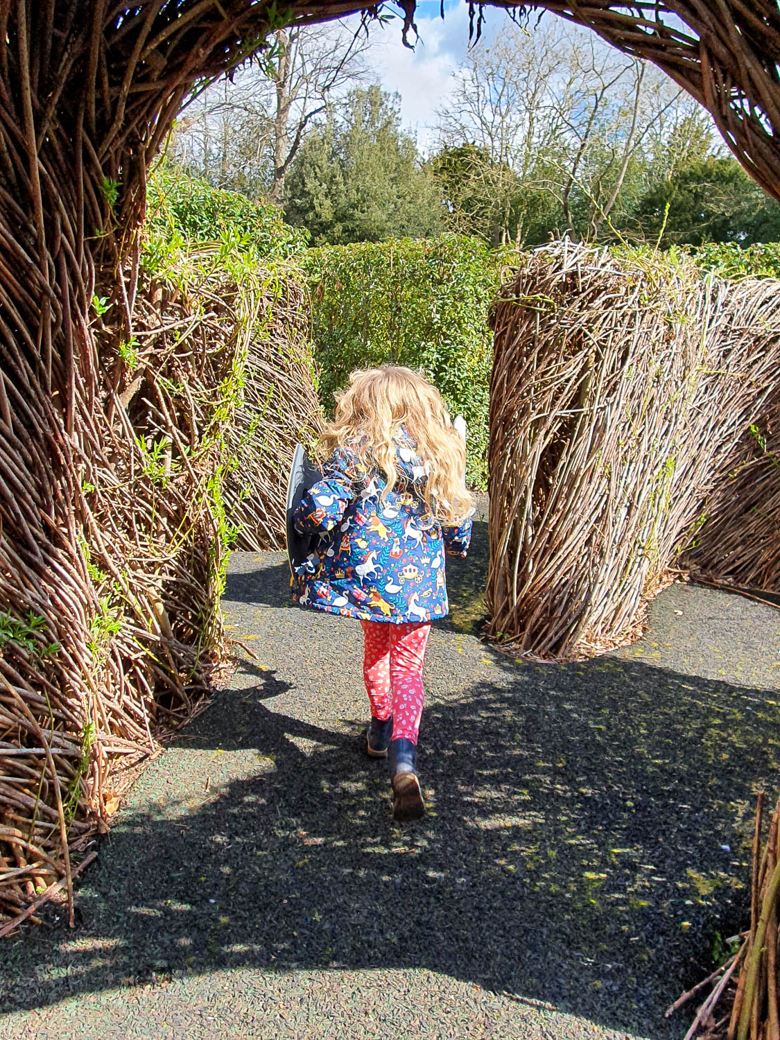 My daughter runs through a wicker tunnel in part of the Horrible Histories maze at Warwick Castle - a visit to Warwick Castle with kids