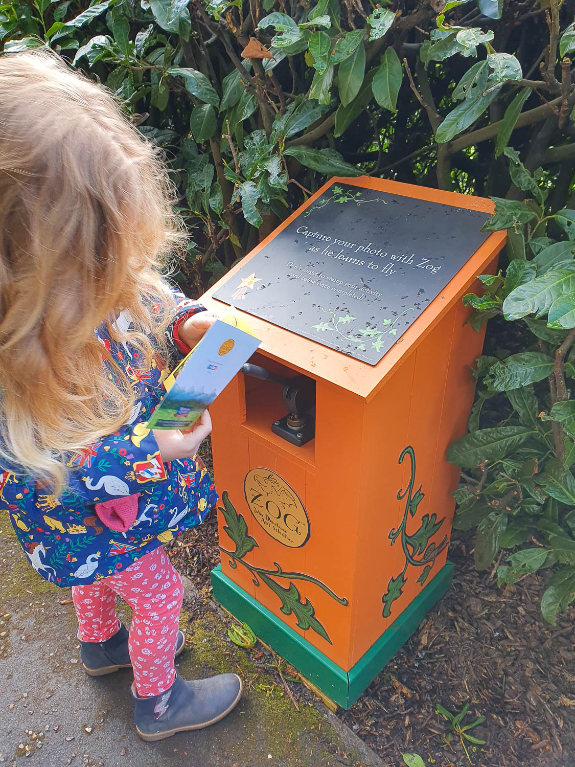 My daughter holds her trail card next to one of the stamp machines for the Zog Trail at Warwick Castle - my review of the Warwick Castle Zog trail