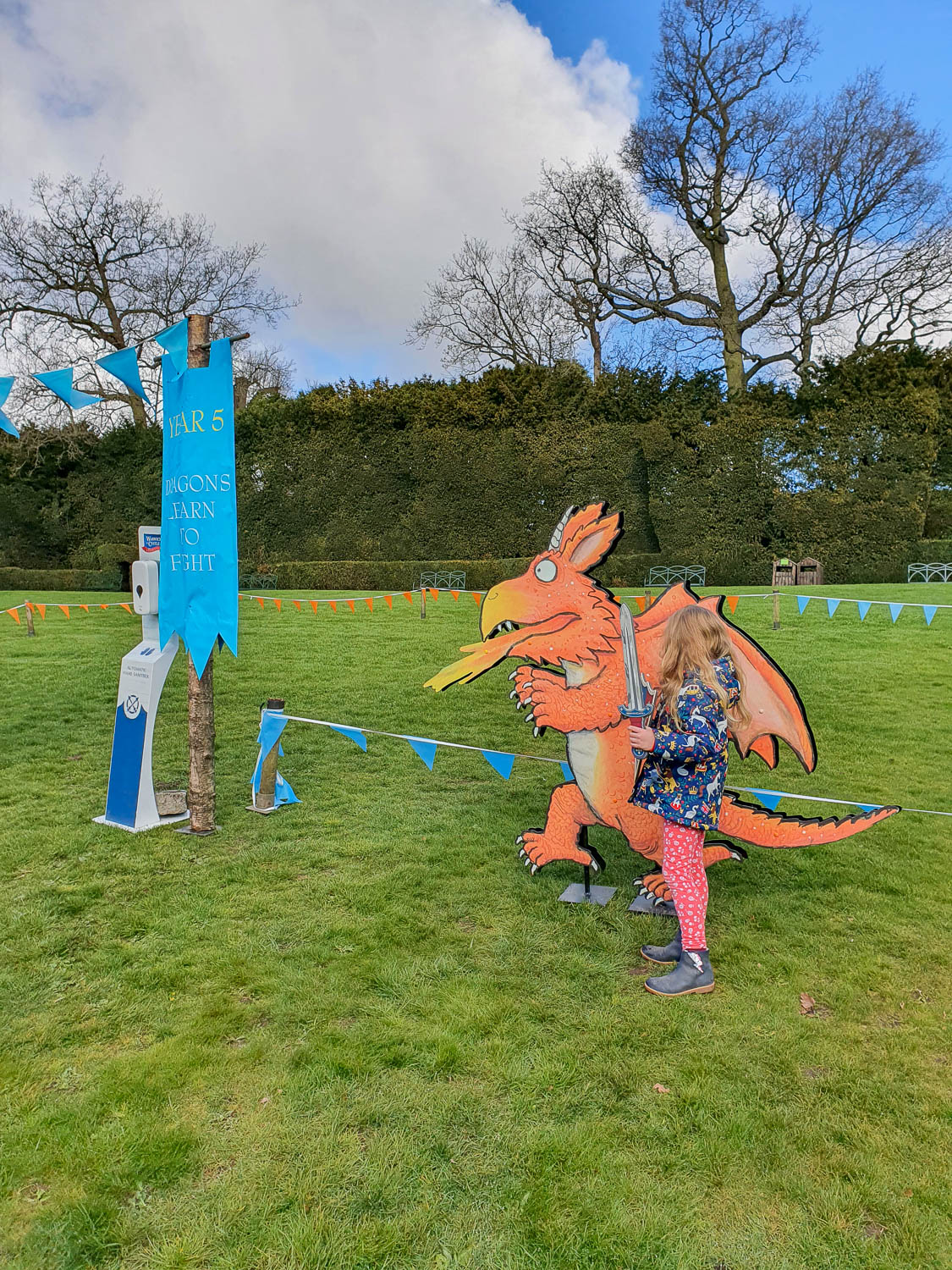 My daughter by Sir Gadabout's swordfighting area next to a picture of Zog the dragon from Julia Donaldson's book, on the Zog trail at Warwick Castle - my review of the Warwick Castle Zog trail