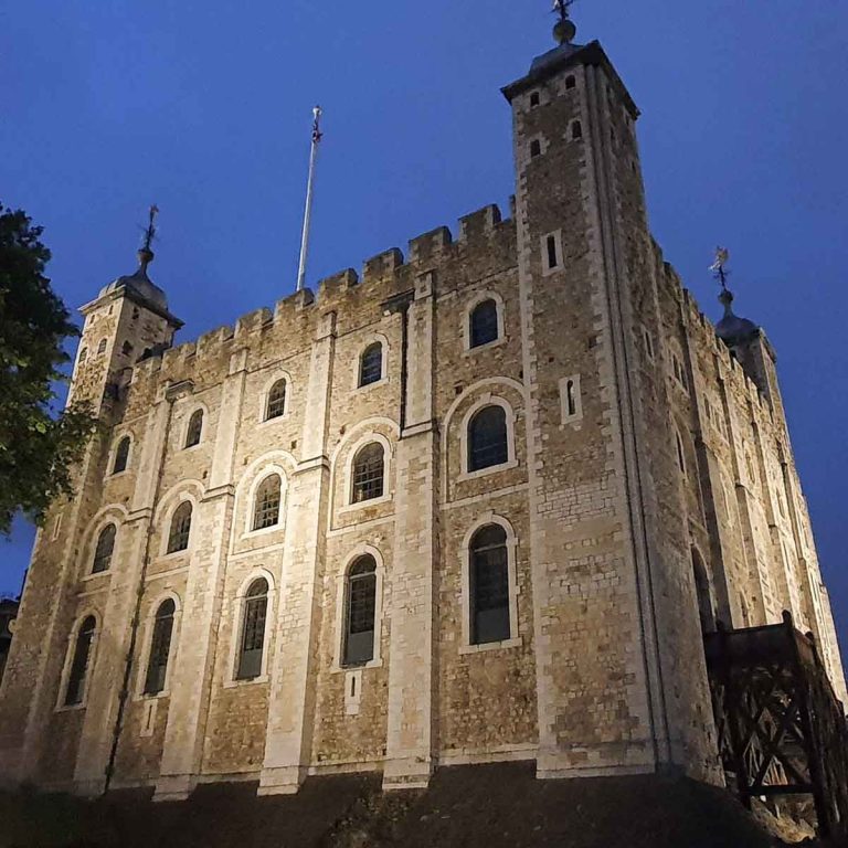 The White Tower at the Tower of London after dark, lit up against a deep blue nighttime sky - my review of seeing the ceremony of the keys with kids