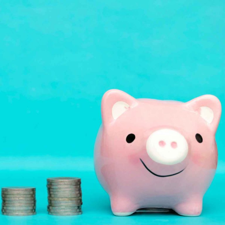 Piggy bank with increasing piles of money next to it against a turquoise background - my top tips for saving money on a city break and holiday