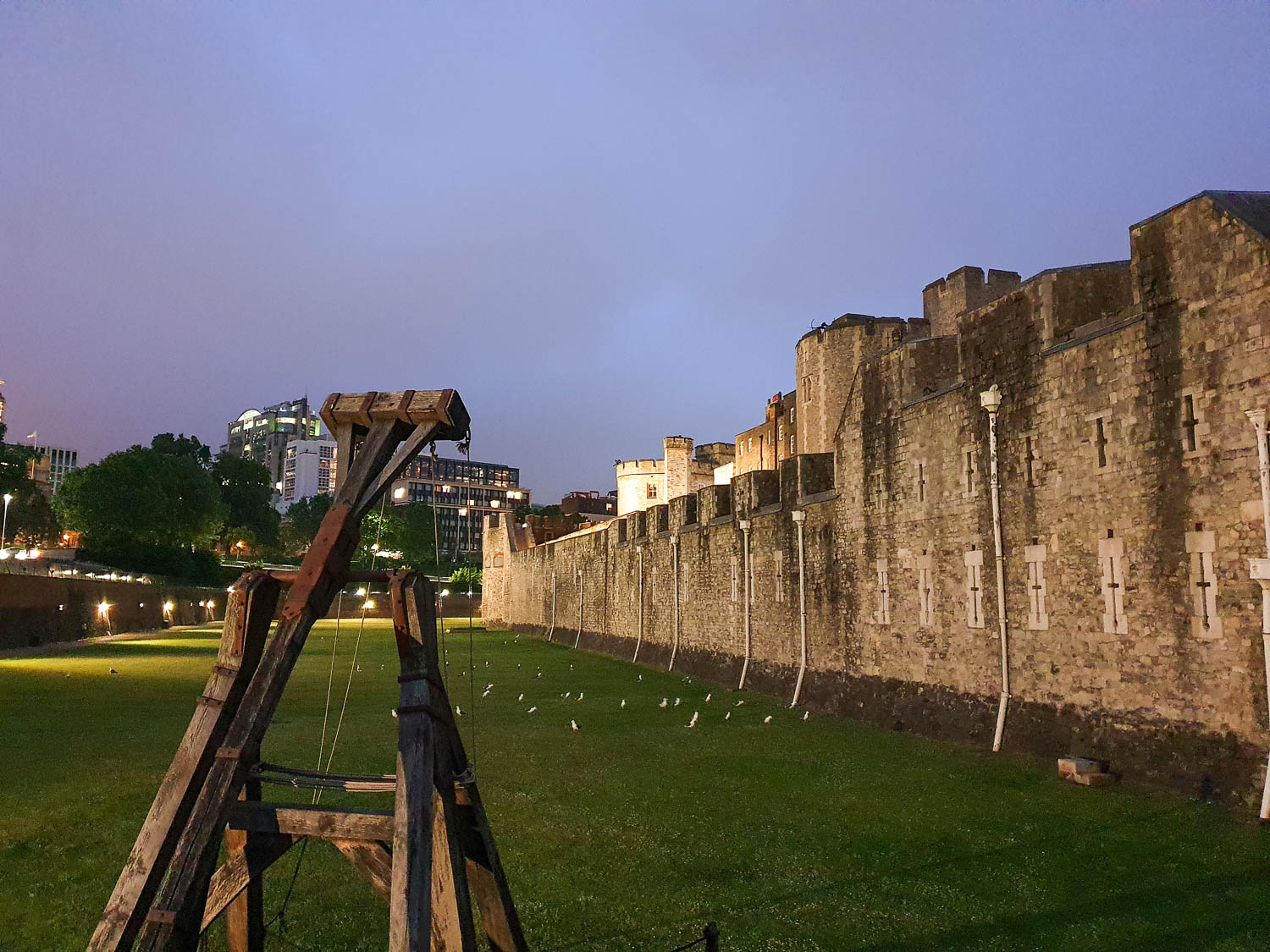 View across the moat at the Tower of London after sunset, with one of the wooden siege weapons shown facing the inner walls - what is it really like at the ceremony of the keys with kids?