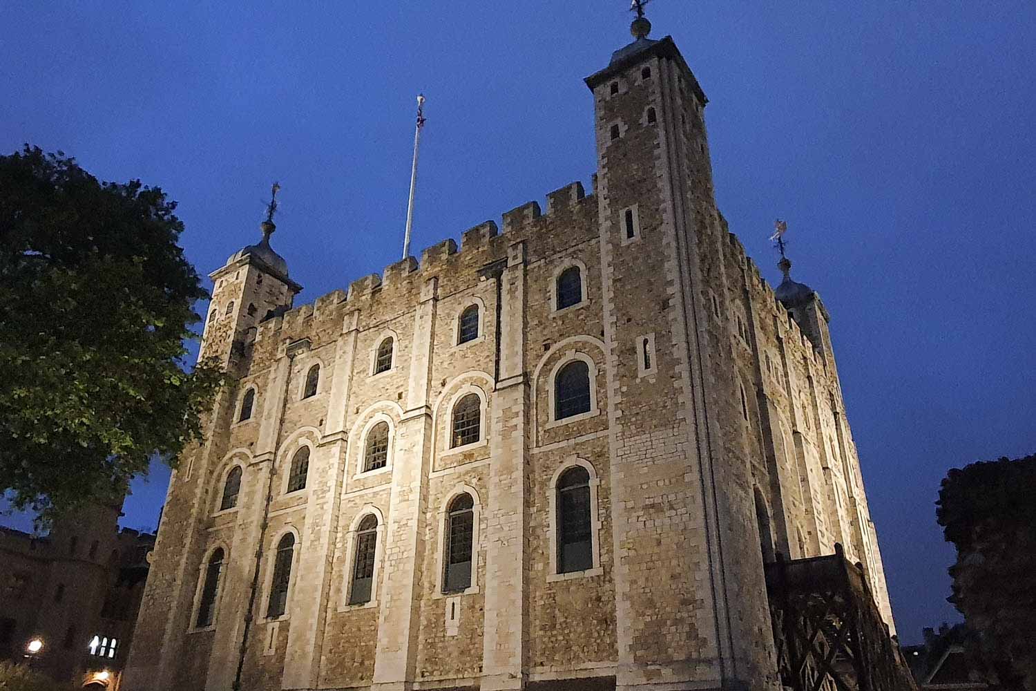The White Tower at the Tower of London after dark, lit up against a deep blue nighttime sky - my review of seeing the ceremony of the keys with kids