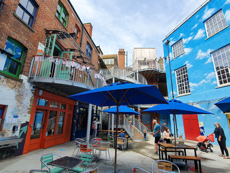 The courtyard at the Story Museum with cafe tables, brightly painted walls and playing cards decorating railings - my review of the Story Museum in Oxford