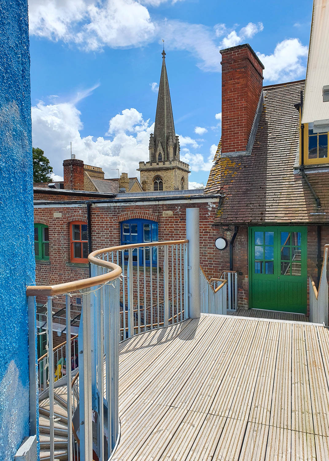 View from the exit of the Enchanted Library, at the top of the stairs above the courtyard with one of the spires of Oxford seen above the buildings with brightly painted windows - my Oxford Story Museum review