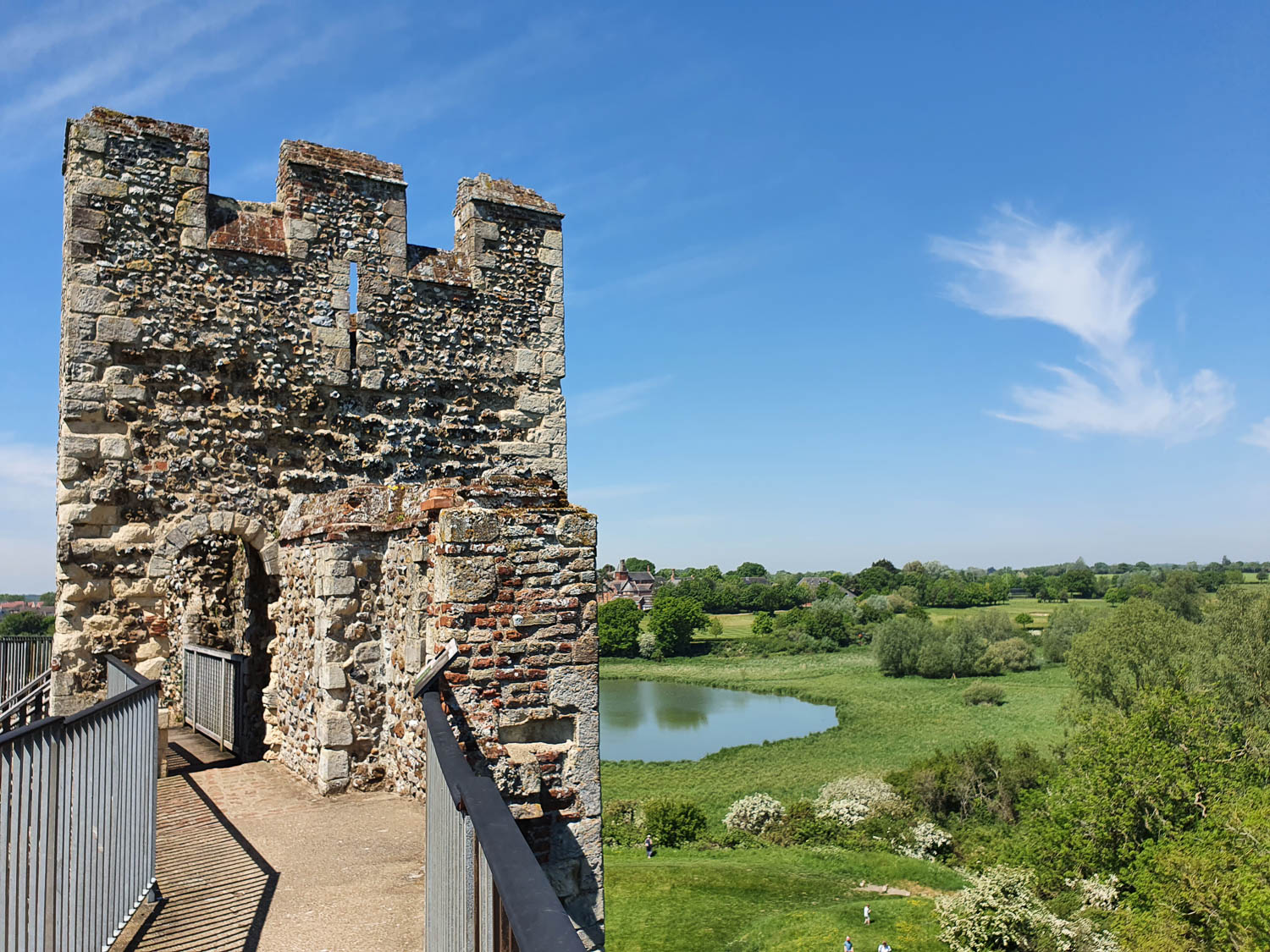 View along the wall walk of Framlingham castle to the grounds and water beyond during a day out in Suffolk with kids