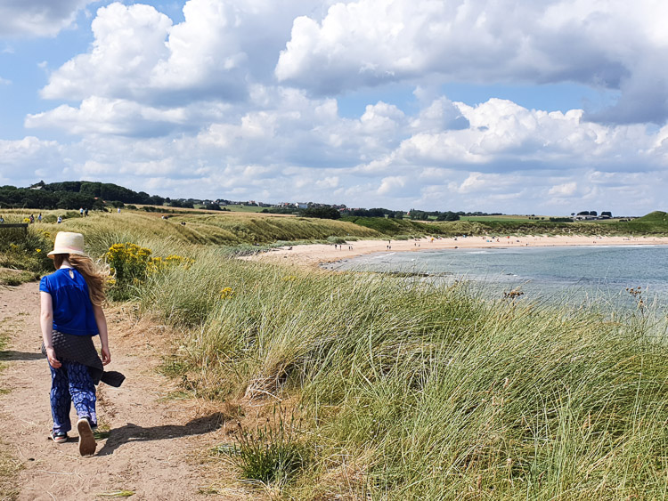 My daughter walks along the cliff path towards Embleton Beach and the sea during our holiday in Northumberland with kids