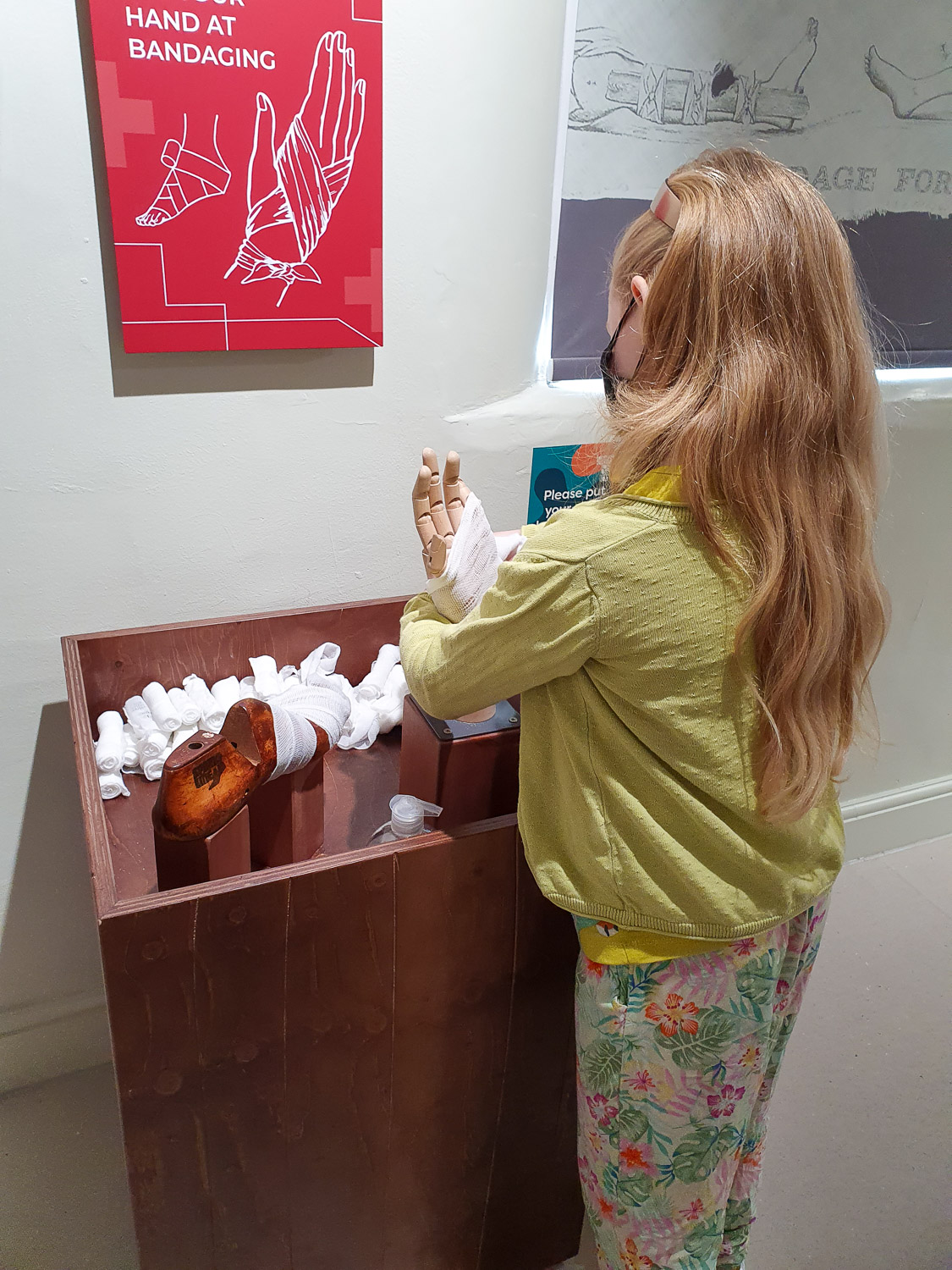 My daughter wraps a model hand in a bandage to see how good she'd be at treating a wound during our visit to the Thackray Museum with kids
