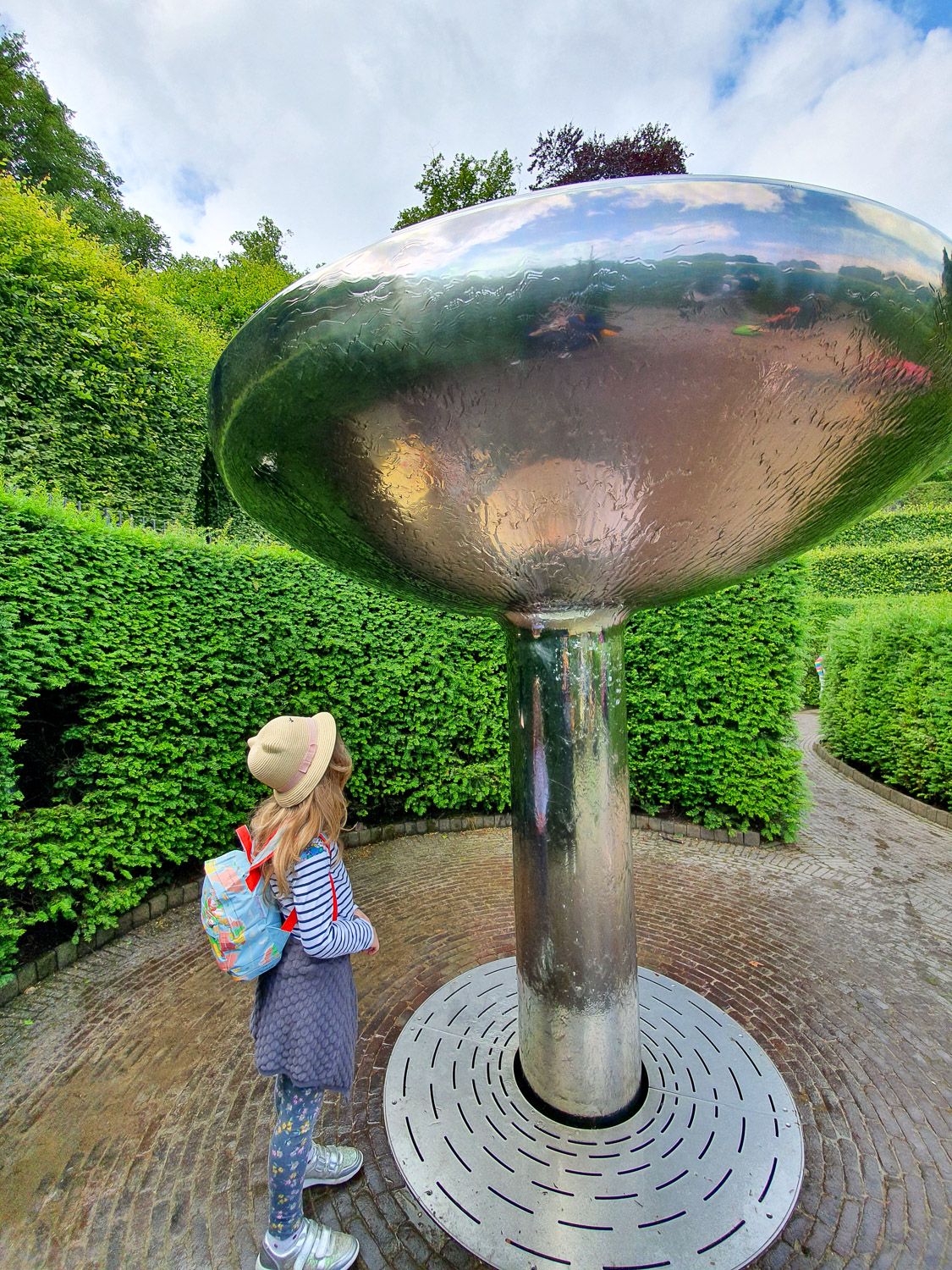 My daughter looks up at the water covering one of the features in the Serpent Garden - one of the best things to do at Alnwick Gardens with kids