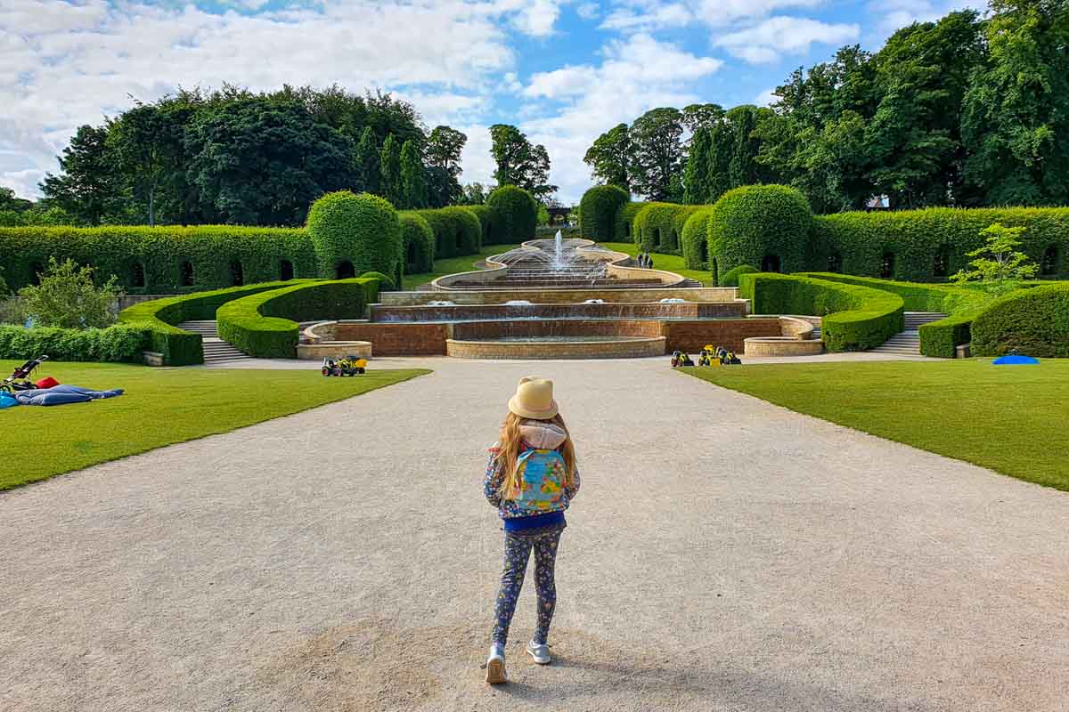 My daughter walks towards the Grand Cascade water feature at the entrance to the Alnwick Garden - one of the great things to do in Northumberland with kids