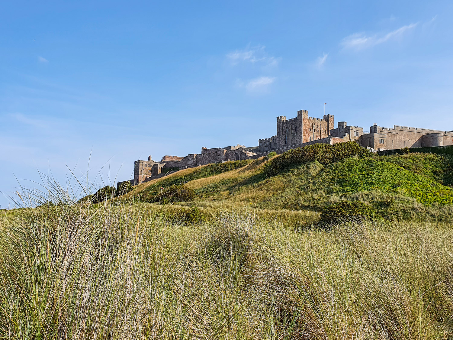 View across the dunes on the beach up towards Bamburgh Castle after a family day out in Northumberland - one of the best parts of the UK for family seaside holidays