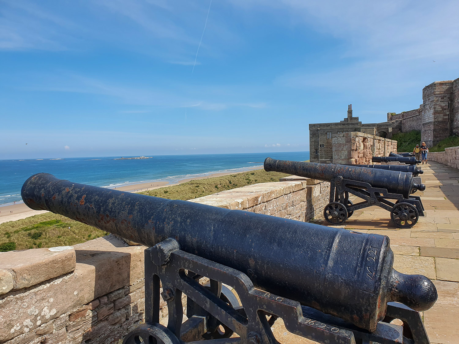 View of a line of cannon pointing out towards the beach and sea on the walls at Bamburgh Castle, Northumberland